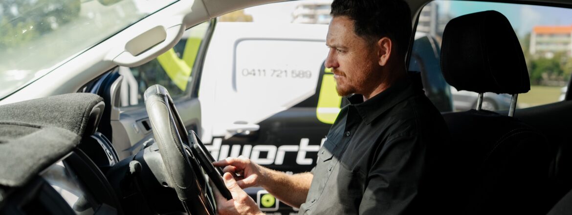 Inspector checking a vehicle interior with a tablet during a QLD COI inspection for rideshare