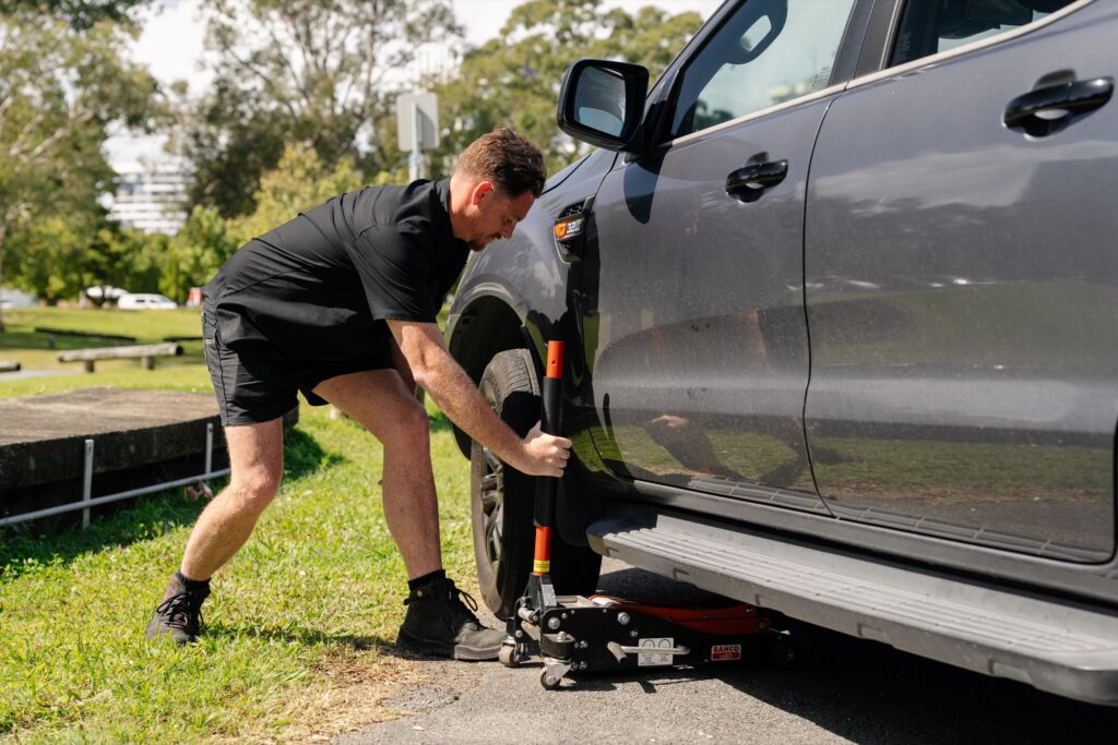 Inspector checking a ute suspension with a trolley jack – safety certificate in Currumbin