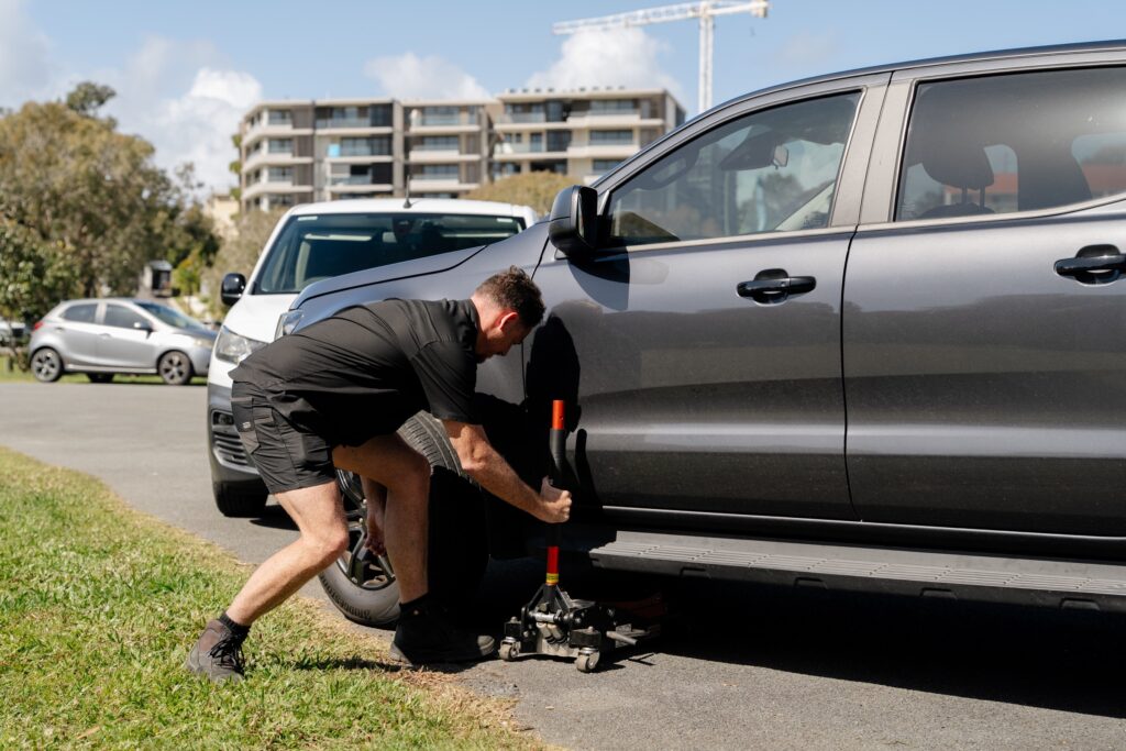 Inspector jacking up a ute to check suspension – mobile safety certificate in Elanora