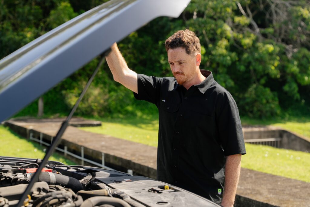 Inspector holding the bonnet up to check the engine bay during a Gold Coast safety certificate inspection