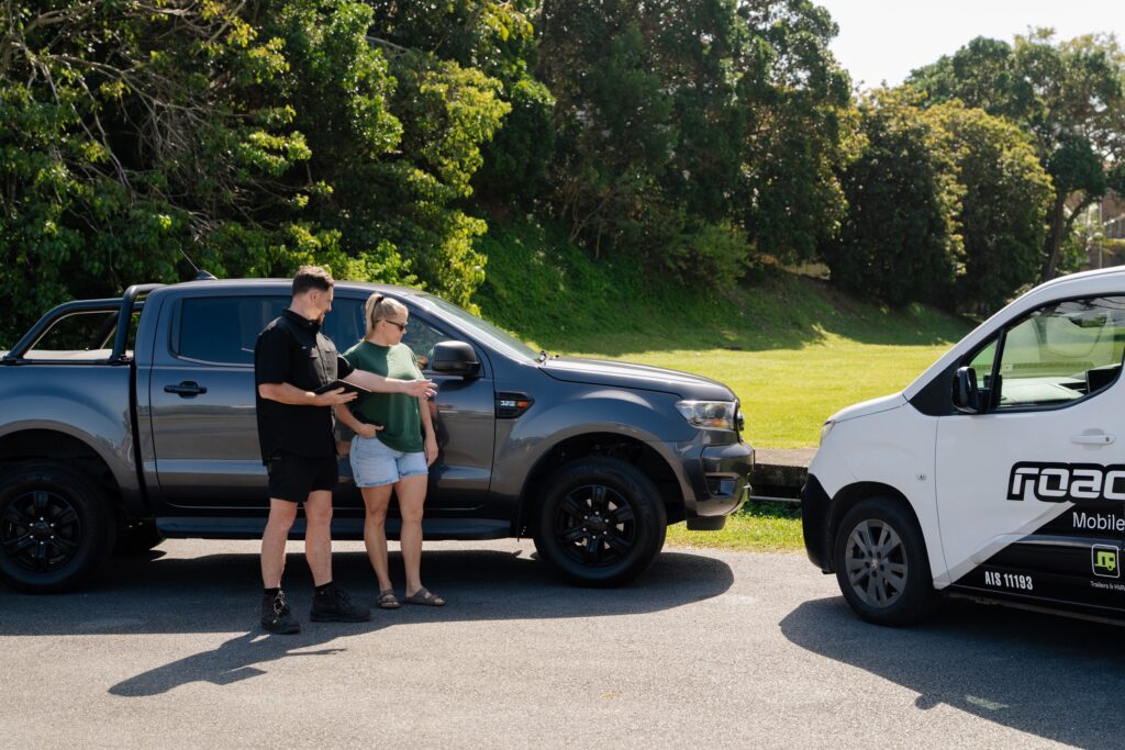 Inspector going through the safety certificate steps with a customer beside the ute on the Gold Coast