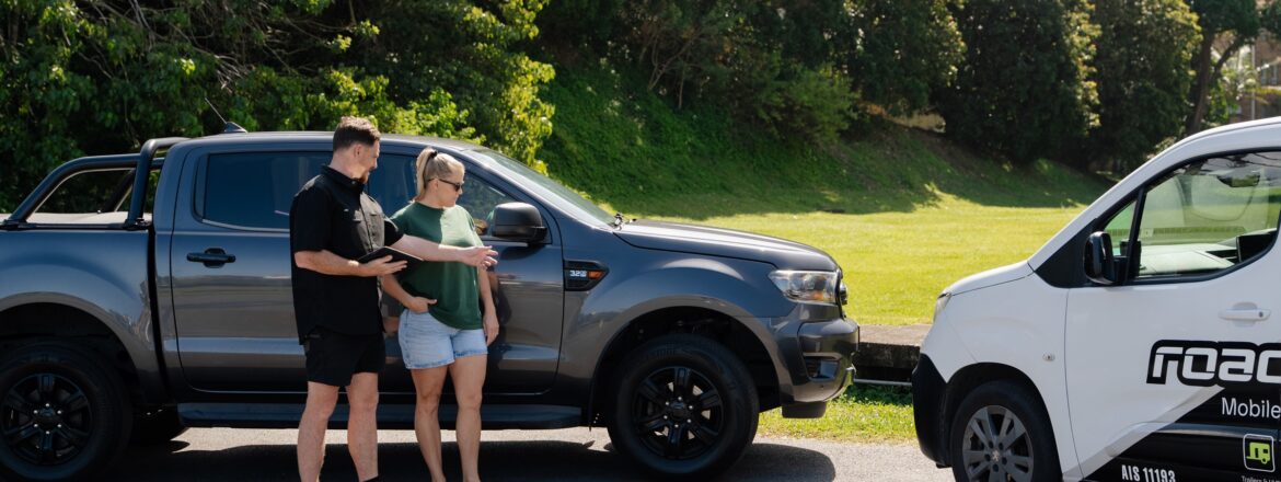 Inspector going through the safety certificate steps with a customer beside the ute on the Gold Coast