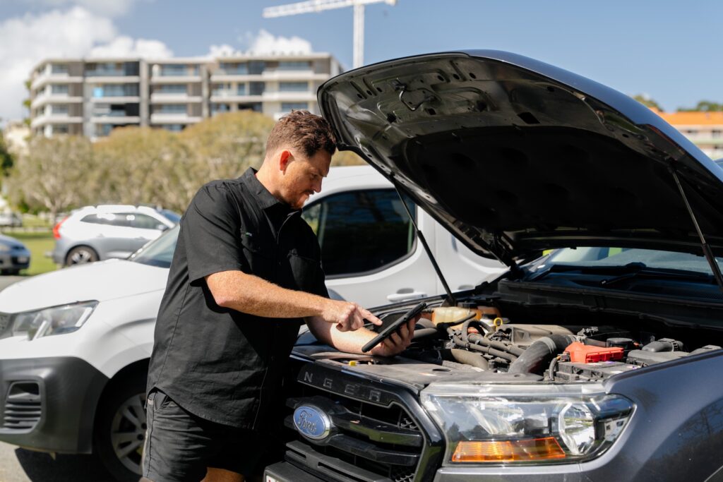 Inspector checking the engine bay with a tablet – mobile safety certificate in Mudgeeraba