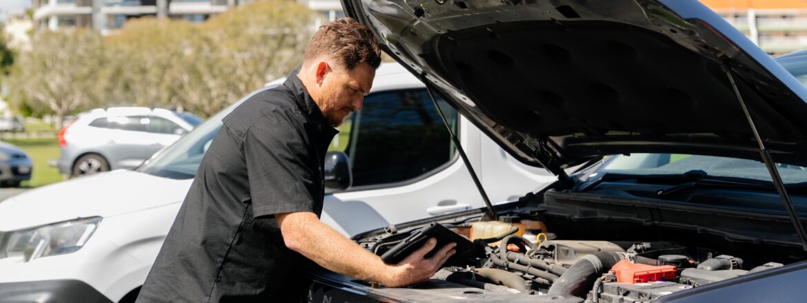 Inspector checking the engine bay with a tablet during a QLD safety certificate inspection