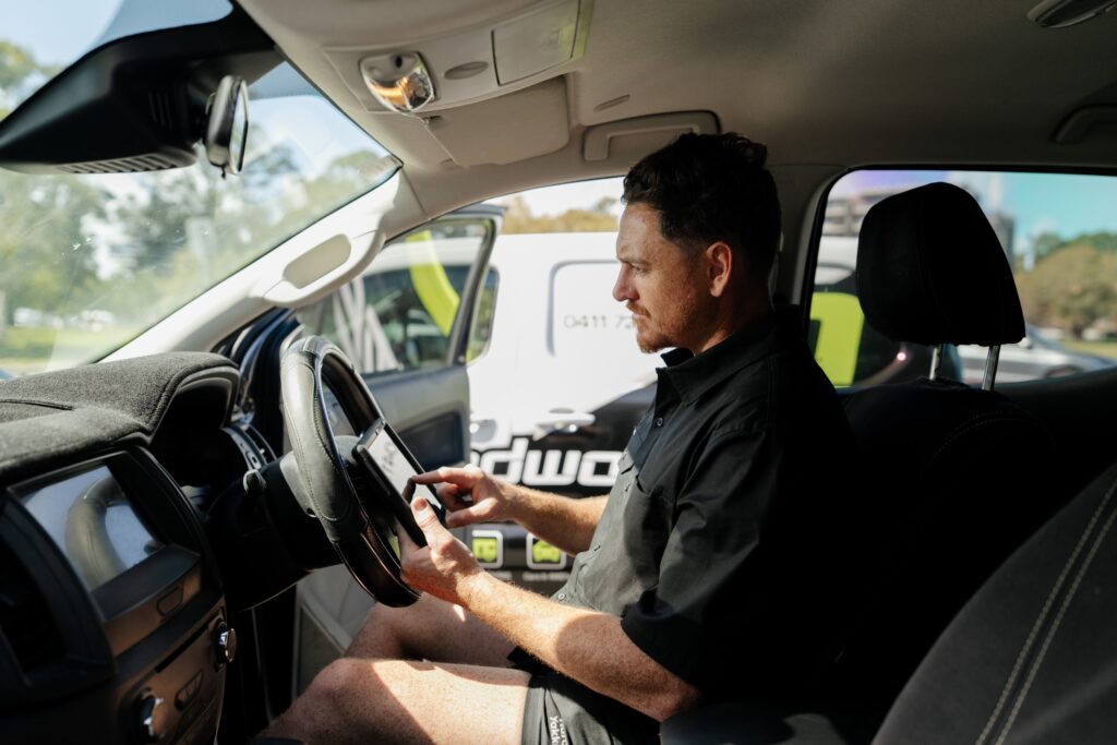 Inspector completing the QLD safety certificate checklist on a tablet inside the car